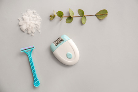Razor, modern epilator and sea salt on light backgroundの写真素材