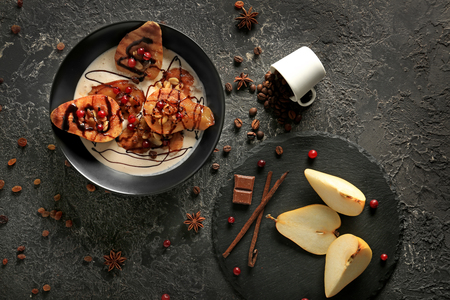 Fresh and baked pears with cream and cranberries on dark tableの写真素材