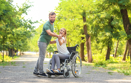 Beautiful woman in wheelchair with man dancing outdoorsの写真素材