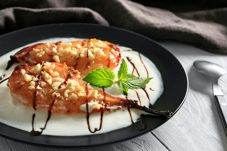 Plate with tasty baked pears and melted ice cream on light wooden tableの写真素材