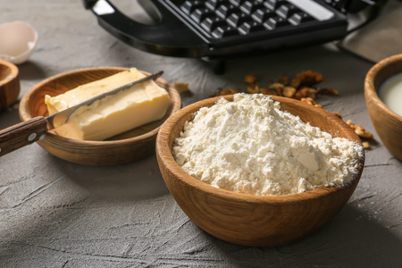 Ingredients for preparing of delicious waffles on grey table
