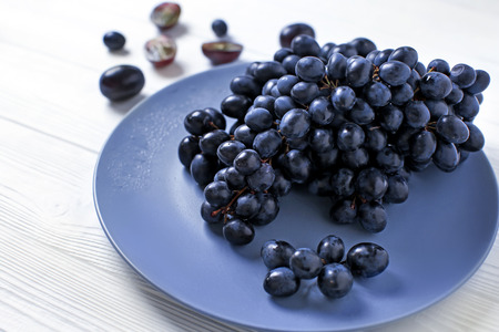 Plate with ripe sweet grapes on light tableの写真素材