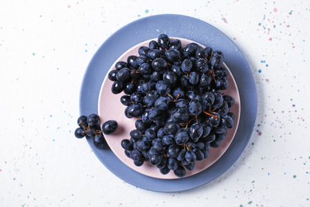 Plates with ripe sweet grapes on light tableの写真素材