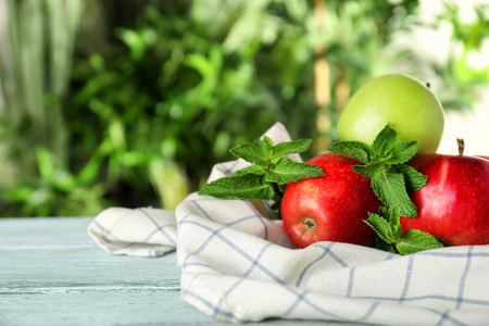 Ripe fresh apples with mint on light wooden tableの写真素材