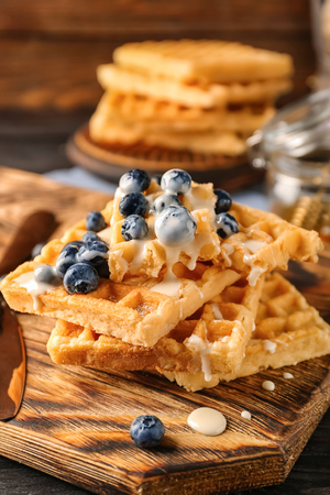 Delicious waffles with sauce and blueberries on wooden boardの写真素材