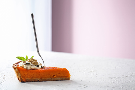 Piece of tasty pumpkin pie with fork on tableの写真素材