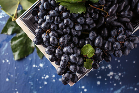 Box with ripe sweet grapes on color tableの写真素材