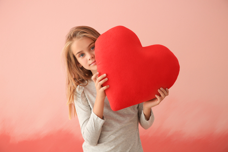 Cute little girl with red heart on color backgroundの写真素材