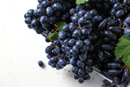 Box with ripe sweet grapes on light table