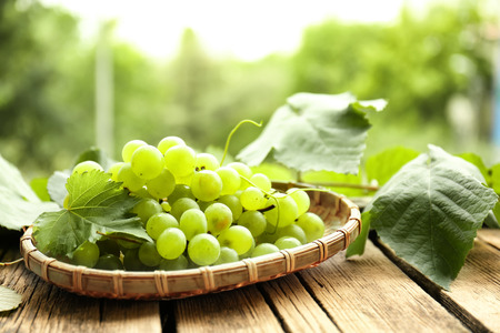 Plate with sweet grapes on wooden table outdoorsの写真素材