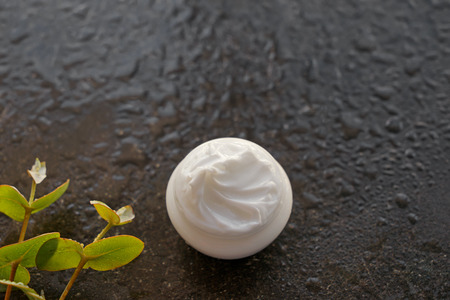 Jar with body cream on dark table