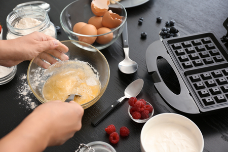 Woman making dough for waffles in kitchenの写真素材