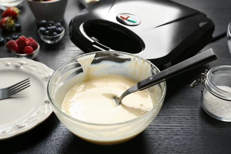 Bowl with dough for waffles on kitchen tableの写真素材