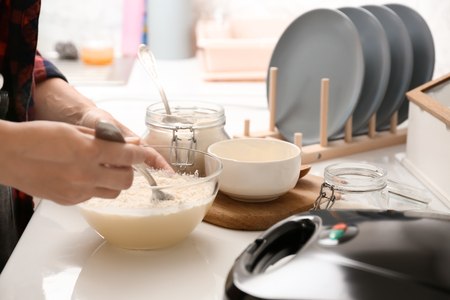 Woman making dough for waffles in kitchenの写真素材