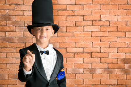 Cute little magician against brick wallの写真素材