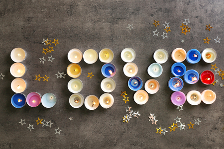 Word LOVE made of colorful candles on dark backgroundの写真素材