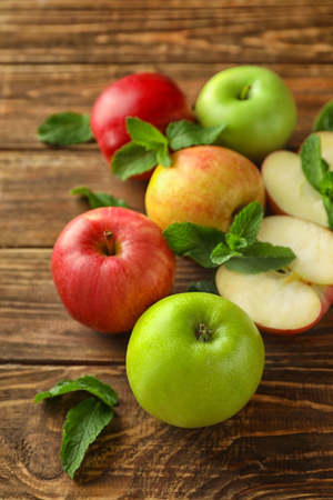 Cut and whole fresh ripe apples with mint on wooden tableの写真素材