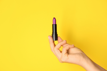 Woman holding bright lipstick on color backgroundの写真素材