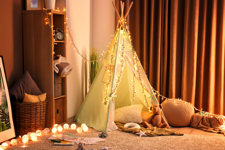 Cozy play tent for kids with glowing garland in room interiorの写真素材