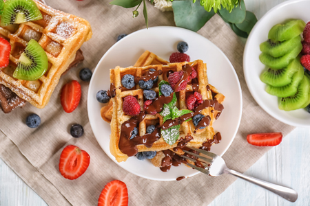 Delicious waffles with berries and chocolate sauce on plateの写真素材
