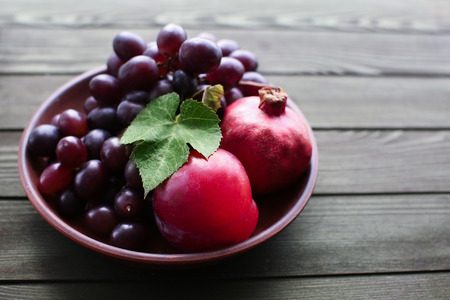 Plate with sweet grapes and pomegranates on wooden tableの写真素材
