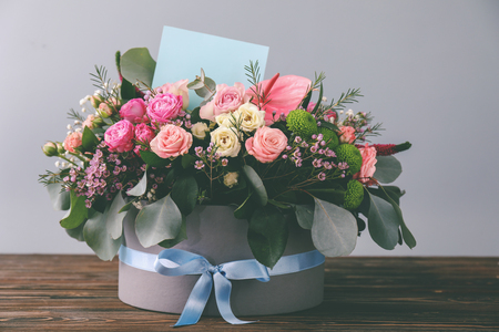 Gift box with beautiful flowers and card on wooden tableの写真素材