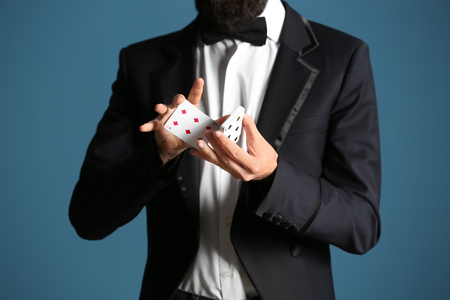 Magician showing tricks with cards on color background, closeupの素材 [FY310115142165]