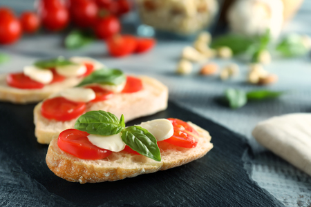 Fresh bread with tomatoes, green basil and mozarella cheese on slate plateの写真素材