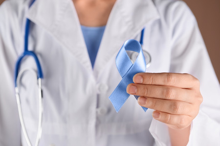 Female doctor holding blue ribbon, closeup. Prostate cancer awareness conceptの写真素材