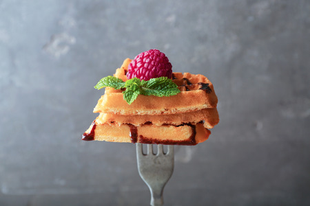 Fork with delicious waffles and chocolate sauce on grey backgroundの写真素材