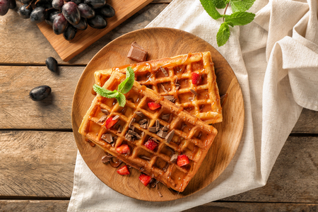 Delicious waffles with strawberries and caramel sauce on wooden plateの写真素材