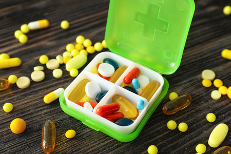 Plastic container with different pills on wooden tableの写真素材