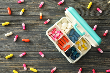 Plastic container with different pills on wooden tableの写真素材