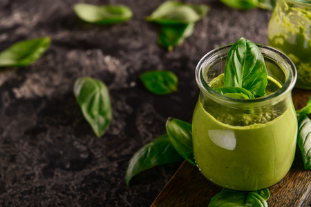 Delicious basil sauce in jar on wooden boardの写真素材