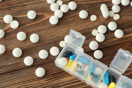 Plastic container with different pills on wooden tableの写真素材