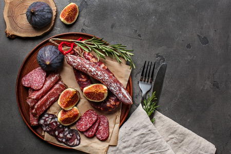 Plate with smoked sausages and figs on tableの写真素材