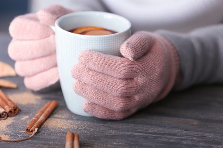 Woman holding cup of delicious mulled wine on wooden table, closeupの写真素材