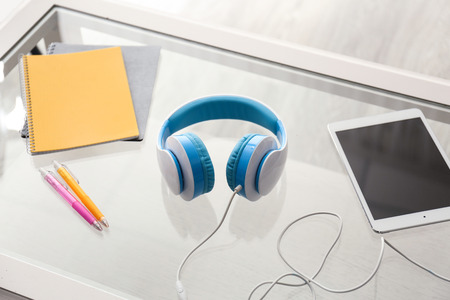 Headphones with tablet PC and stationery on glass tableの写真素材