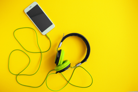 Headphones with mobile phone on color backgroundの写真素材