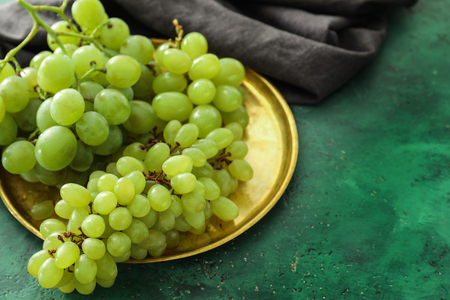 Metal tray with ripe juicy grapes on color tableの写真素材