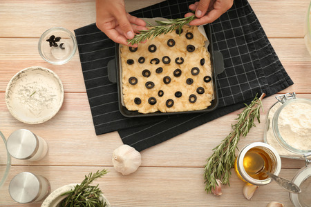 Woman preparing traditional Italian Focaccia on wooden tableの写真素材