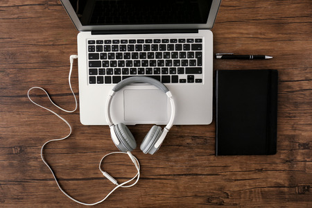 Headphones with laptop and notebook on wooden tableの写真素材