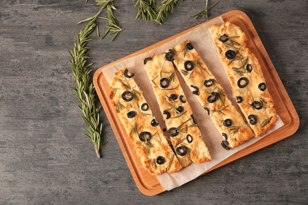 Traditional Italian Focaccia with rosemary and olives on grey tableの写真素材