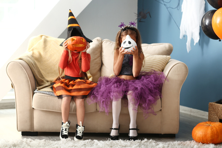 Cute little girls in Halloween costumes at homeの写真素材