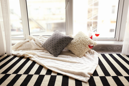 Cozy place for rest with soft pillows and wine near window