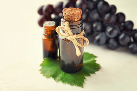 Bottles with oil and fresh ripe grapes on white backgroundの写真素材
