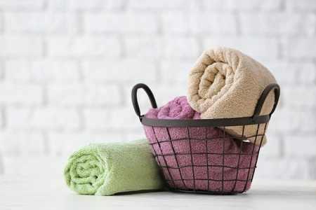 Metal basket with clean soft towels on white tableの写真素材
