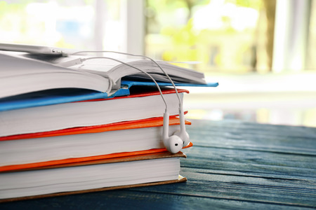 Stack of books with earphones on table, closeup. Concept of audiobookの写真素材