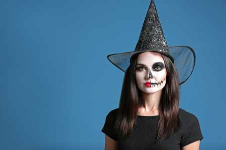 Beautiful woman dressed as witch for Halloween on color background
