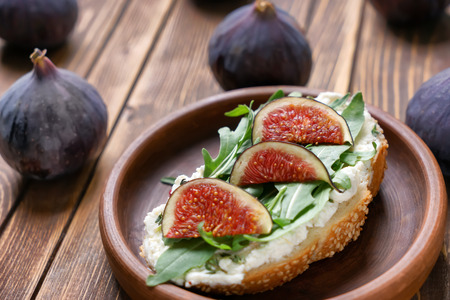 Tasty sandwich with ripe fig, herbs and cream cheese on plateの写真素材